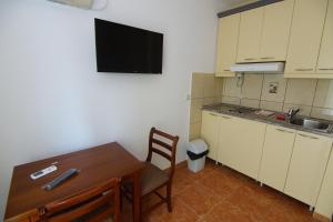 a kitchen with a table and a television on the wall at Blue Palace Guest House in Budva