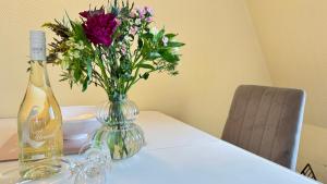 a bottle of wine and a vase of flowers on a table at Syltrose Whg 1b in Westerland (Sylt)