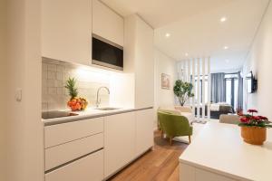 a kitchen with white cabinets and a living room at Host Wise - Marquesa Palace in Porto