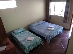 two beds in a small room with a window at Recanto da Mata Morretes in Morretes