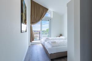 a bedroom with a bed and a large window at Vakantiewoning aan het water - met 4 balkons - Vista Maris - Nr 30 in Sint Annaland
