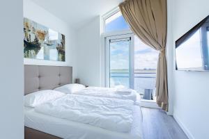 a white bedroom with a bed and a window at Vakantiewoning aan het water - met 4 balkons - Vista Maris - Nr 30 in Sint Annaland