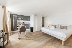a bedroom with a large white bed and a kitchen at Bord de l'eau 2 - Studio - Sea view in Cancale