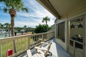 a porch with a chair and palm trees on a house at 1644 Courtside Villa in Seabrook Island