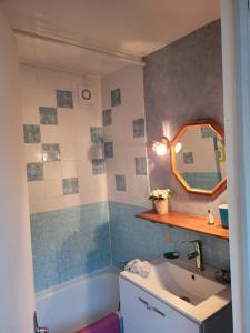a bathroom with a sink and a mirror and a tub at la petite maison in Granville