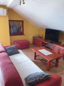 a living room with a couch and a tv and a table at Apartmani Štulec in Preko