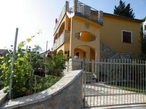 a yellow house with a fence in front of it at Apartmani Štulec in Preko