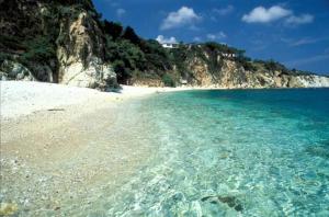 a beach with clear blue water and a mountain at Monolocale Eco del Mare in Portoferraio +3 photos