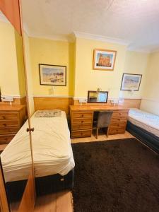 een slaapkamer met 2 bedden en een bureau met een computer bij Saxonia guest house in Weston-super-Mare