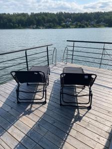 two chairs sitting on a dock near a body of water at Bo på husbåt med egen badplats in Gamleby