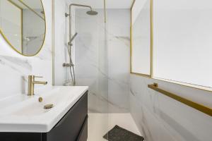 ein weißes Badezimmer mit Waschbecken und Spiegel in der Unterkunft Naturiste Cap d'Agde Héliopolis Eden Suite in Cap d'Agde + 22 Fotos