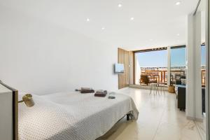 ein weißes Schlafzimmer mit einem Bett und einem großen Fenster in der Unterkunft Naturiste Cap d'Agde Héliopolis Eden Suite in Cap d'Agde