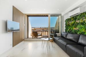 ein Wohnzimmer mit einer schwarzen Couch und einer großen grünen Wand in der Unterkunft Naturiste Cap d'Agde Héliopolis Eden Suite in Cap d'Agde