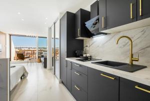eine Küche mit schwarzen Schränken und einer Spüle in der Unterkunft Naturiste Cap d'Agde Héliopolis Eden Suite in Cap d'Agde