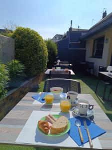 a table with a plate of bread and orange juice at Escal Hôtel in Étaples +27 photos