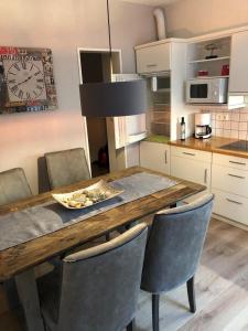 eine Küche mit einem Holztisch mit Stühlen und einer Uhr in der Unterkunft DünenZeit in List