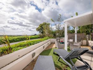 un patio con sillas y una pérgola blanca en Cosy Cabin for Two with Lovely Countryside Views, Near Kingsbridge, en Churchstow