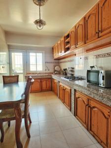 uma grande cozinha com armários de madeira e uma mesa em logement exceptionnel réservé aux familles em Meknès
