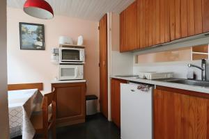 Una pequeña cocina con fregadero y microondas. en Sapins A5 - Résidence Super Murat, en Murat-le-Quaire