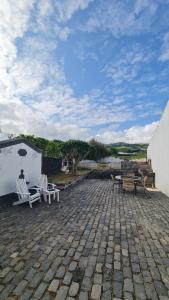 a patio with two chairs and a table and benches at Tainhas Village - Vila Franca do Campo in Ribeira das Tainhas