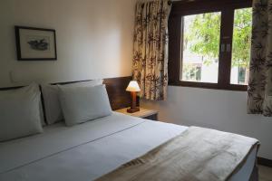 a bedroom with a large white bed with a window at Hotel Fazenda Portal de Gravatá in Gravatá