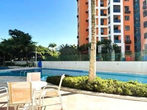 Una mesa y sillas junto a una piscina. en Apartamento com Estrutura de Hotel na Barra, en Río de Janeiro 9 fotos más