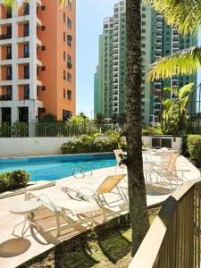 Un grupo de sillas y una piscina con edificios. en Apartamento com Estrutura de Hotel na Barra, en Río de Janeiro