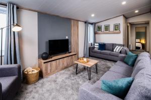 a living room with a couch and a tv at Hot Tub Lodge, Victory Liberte 104 in St. Andrews
