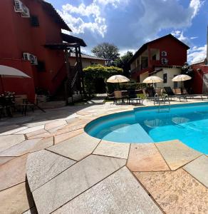 a swimming pool next to a building with tables and chairs at Villa Zen Pirenópolis Conforto e Bem-Estar in Pirenópolis