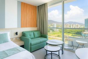 a hotel room with a bed and a chair and a window at Porto Horizonte Apartamentos in Santa Marta