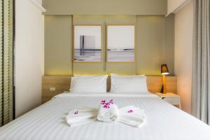 Un dormitorio con una cama blanca con toallas. en Snoozz Hotel Krabi, en Krabi