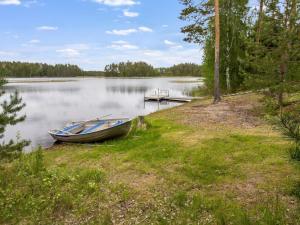 a boat on the shore of a lake with a dock at Holiday Home Kaunotar by Interhome in Savitaipale