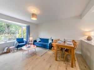 a living room with a table and a blue couch at Seashell Haven in Beadnell