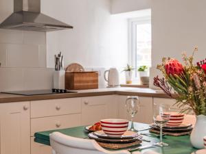 a kitchen with a table with plates and wine glasses at Holiday Home Cobble Cottage by Interhome in Lerryn