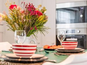 a table with two cups and a vase of flowers at Holiday Home Cobble Cottage by Interhome in Lerryn