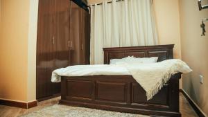 a bedroom with a wooden bed with white sheets at NJIRO 4BDR FAMILY HOME NEAR RESTURANTs AFCON EXERCISE Field in Arusha