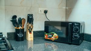 a black microwave sitting on a kitchen counter with utensils at NJIRO 4BDR FAMILY HOME NEAR RESTURANTs AFCON EXERCISE Field in Arusha