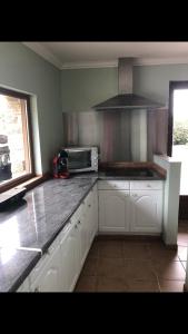 a kitchen with white cabinets and a microwave at Petite maison de campagne avec jacuzzi in Lannéanou