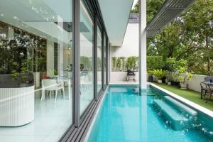 einen Innenpool in einem Haus mit Glaswänden in der Unterkunft Modern Luxury Poolhaus with Lift in Klong Toi