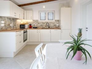 a kitchen with white cabinets and a table with a potted plant at Holiday Home Sova by Interhome in Nečujam