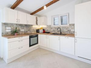 a kitchen with white cabinets and a sink at Holiday Home Sova by Interhome in Nečujam