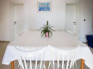a white dining room table with white chairs and a plant at Holiday Home Sova by Interhome in Nečujam