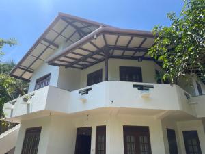 una casa con un balcón encima en Three Brothers Villa, en Mirissa