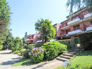 a pink building with a palm tree and flowers at Apartment Villa Castiglioni by Interhome in Luino
