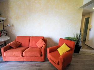 two orange chairs and a couch in a living room at Apartment Villa Castiglioni by Interhome in Luino