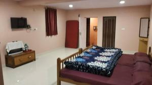 uma sala de estar com um sofá e uma televisão em Sousam Cottage em Kodaikānāl mais 4 fotografias