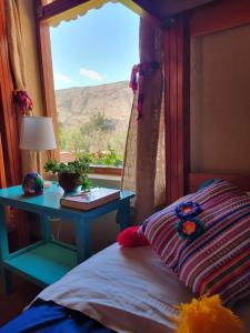 a bedroom with a window with a bed and a table at Charming Urubamba Cusco house - Kapuliyuq in Urubamba