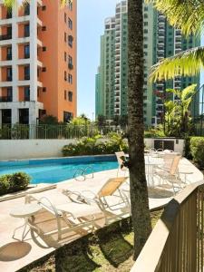 un patio con sillas y una piscina con edificios. en Apartamento com Estrutura de Hotel na Barra, en Río de Janeiro 11 fotos más