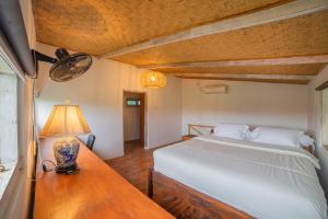 a bedroom with a bed and a table with a lamp at The Sri Loft in Dalung