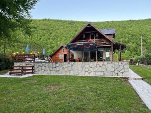 a log cabin with a stone wall in front at Property with your own beach and pool - Whispering Waters in Krupa na Vrbasu